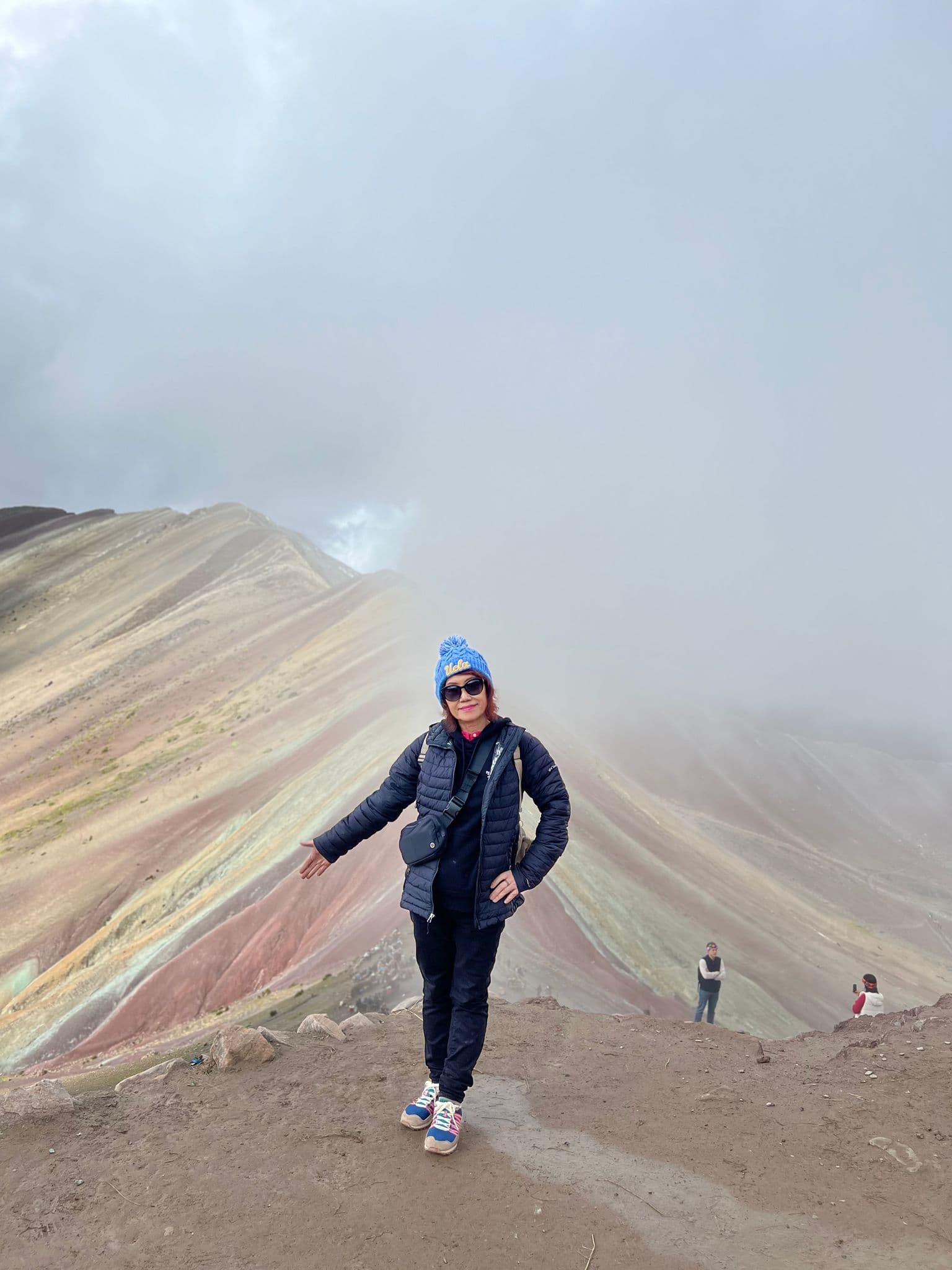 Vinicunca (Rainbow Mountain) in Cusco, Peru with a traveler posing at the colorful ridge during a trip