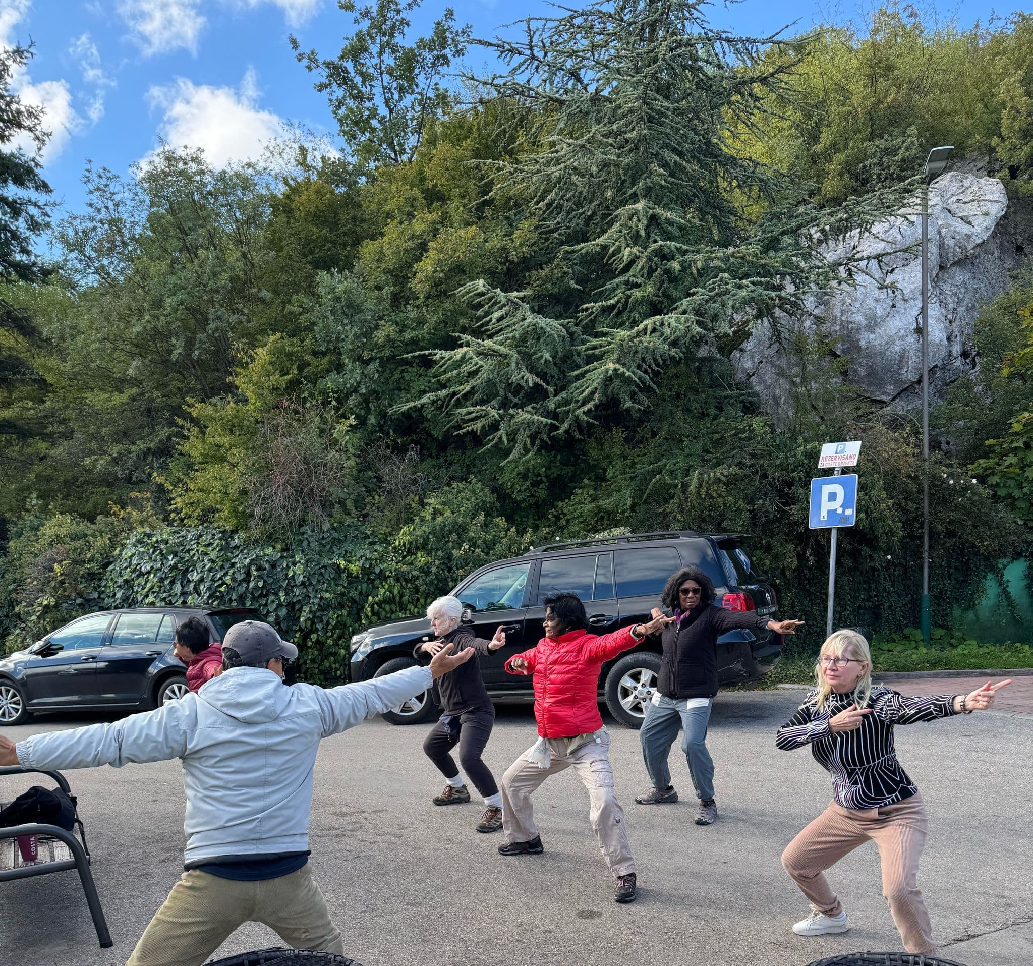 Group of travelers practicing Tai Chi in a parking lot by a gas station in Montenegro.