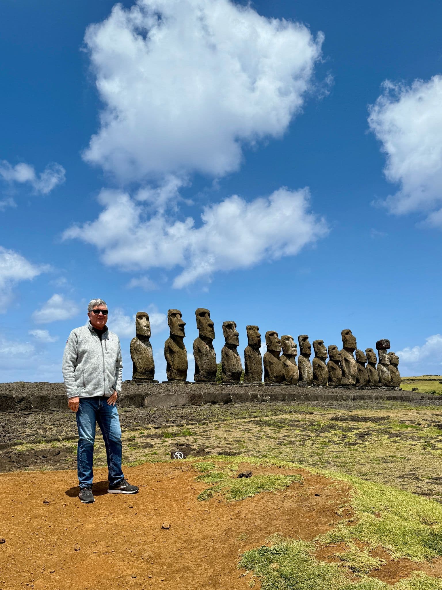 Ahu Tongariki moai statues in a row with a man standing and posing in front on Easter Island, Chile.