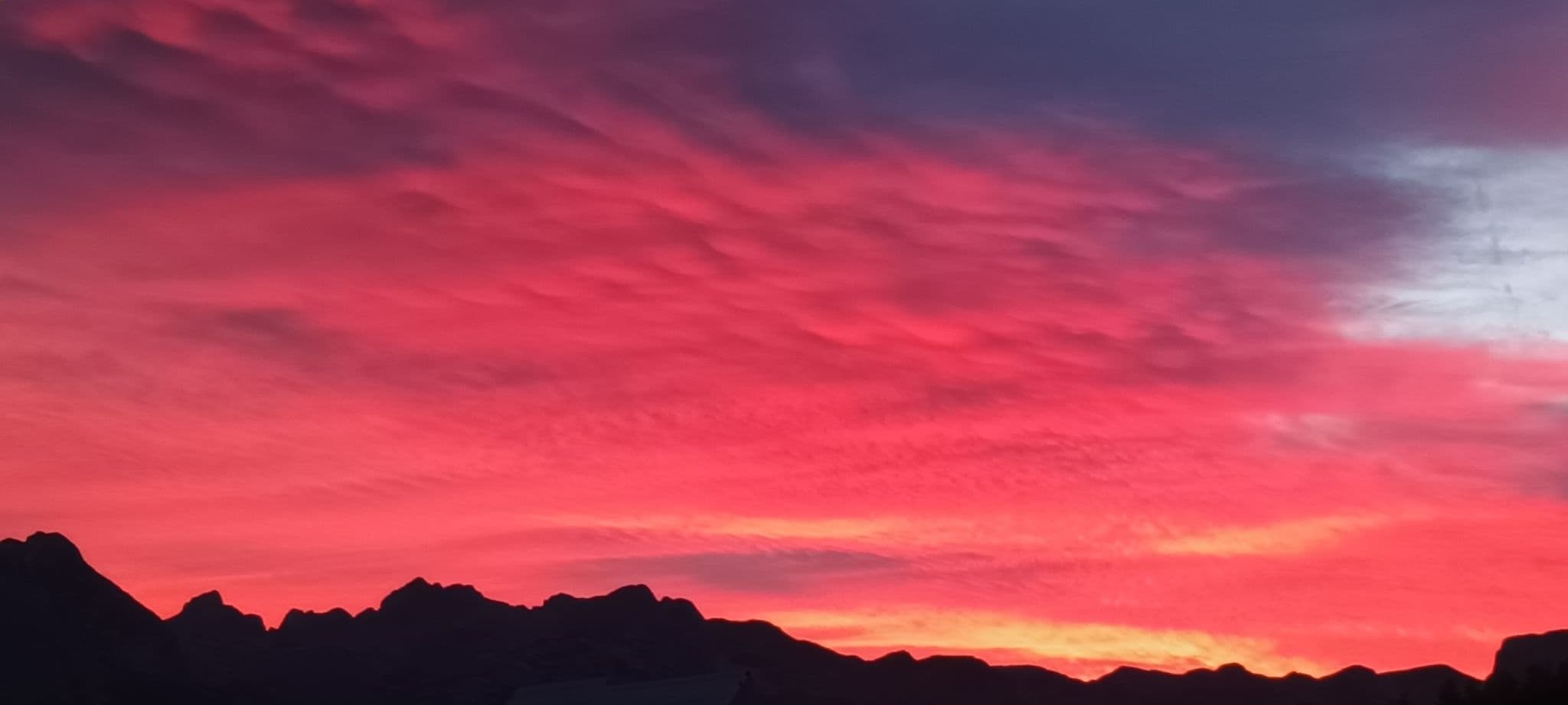 Vibrant pink and purple sunset sky over silhouetted mountain peaks in Durmitor National Park, Montenegro.