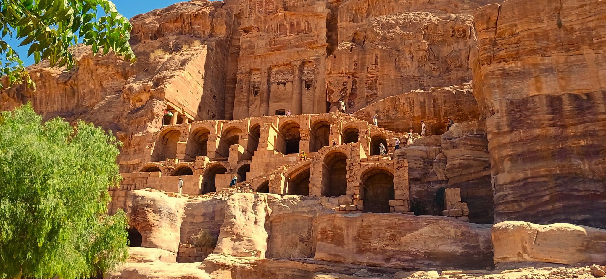 Royal Tombs carved into sandstone cliffs at Petra with visitors on the terraces, Petra, Jordan.