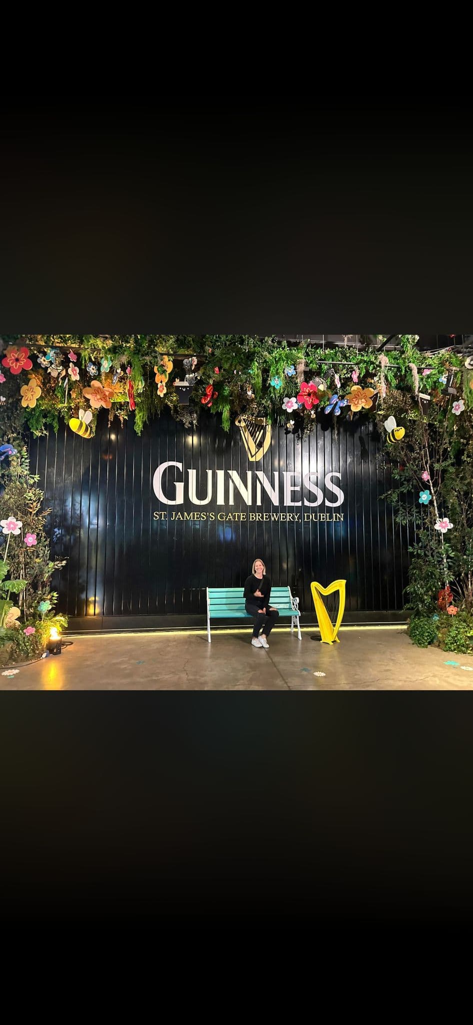 Guinness Storehouse sign at St. James's Gate Brewery with a person sitting on a bench inside the visitor area, Dublin, Ireland.