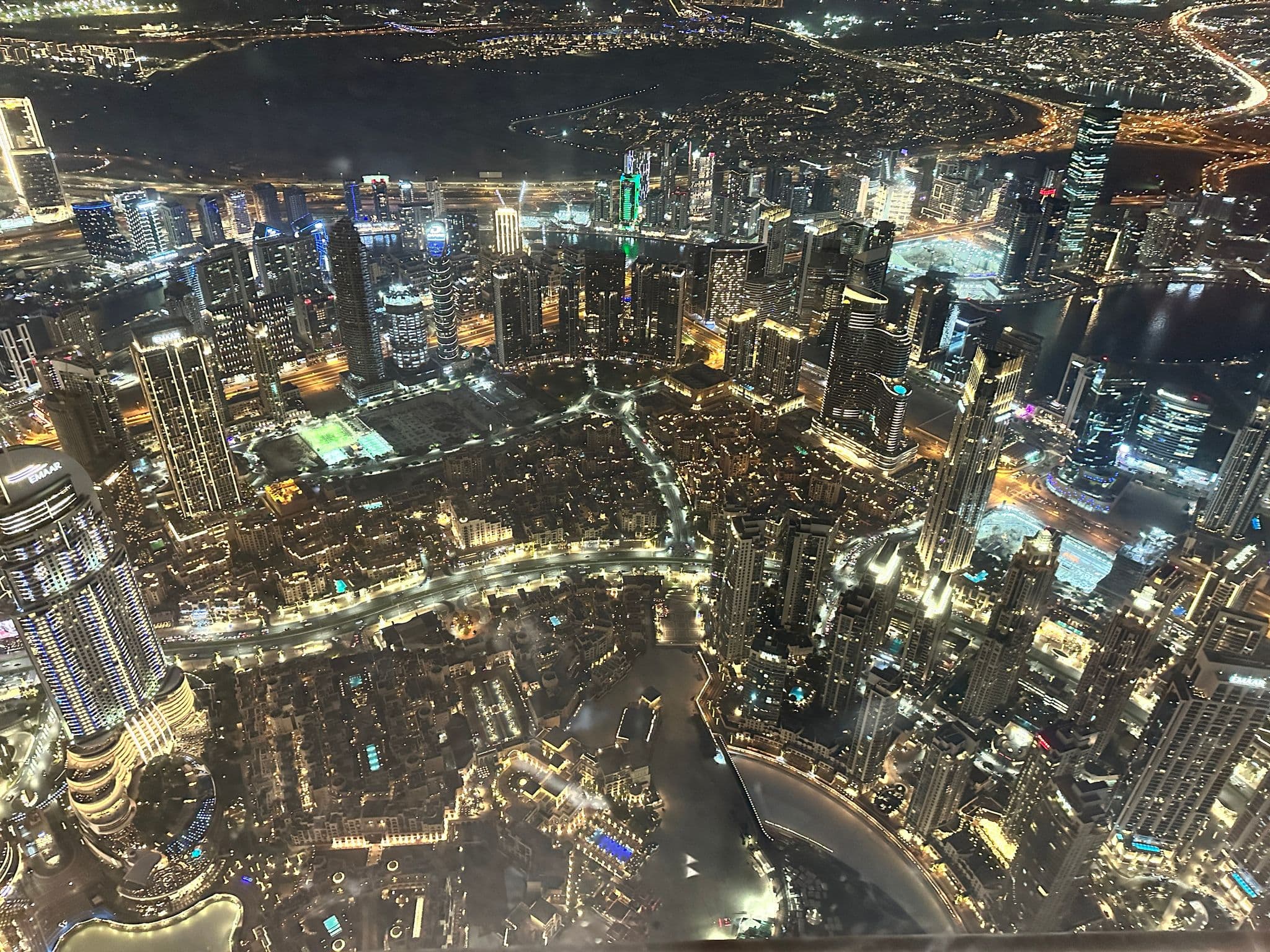 View from the top of the Burj Khalifa over Downtown Dubai at night, showing illuminated skyscrapers and the Dubai Fountain, United Arab Emirates