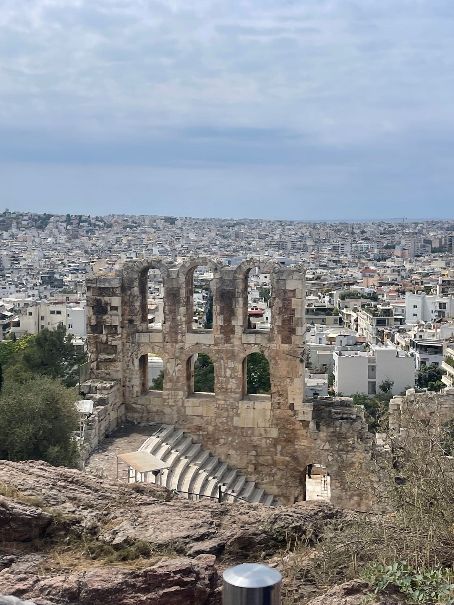 Odeon of Herodes Atticus ruins with arched walls and tiered stone seating overlooking Athens, Greece.