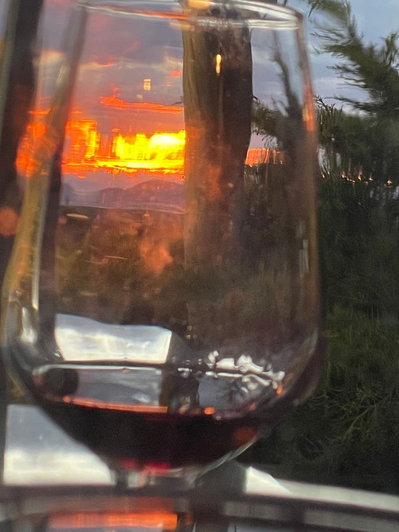 Wine glass reflecting a colorful sunset over Athens, Greece, seen from a terrace during a trip.