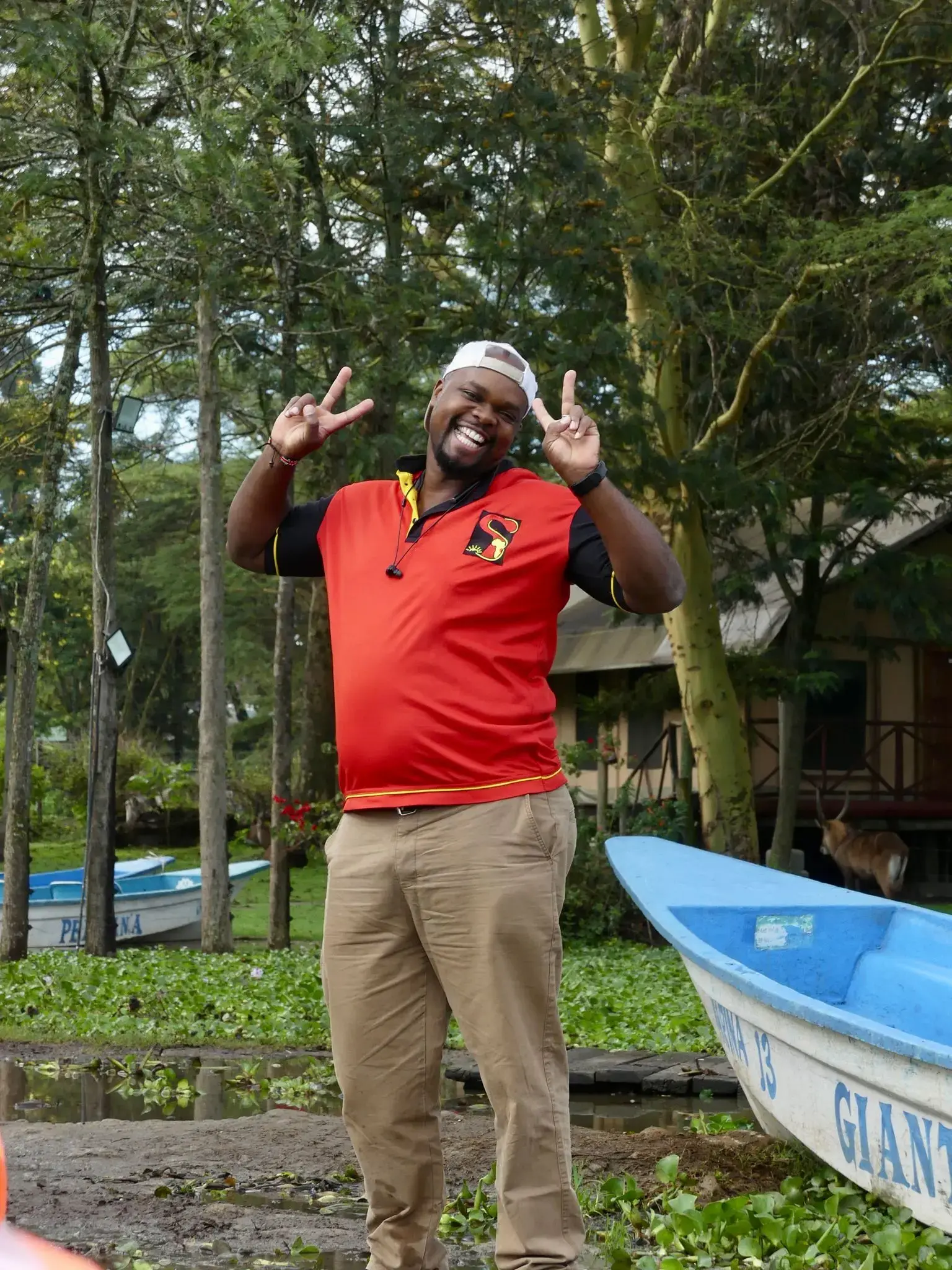 Guide posing with peace signs beside boats on Lake Naivasha, Naivasha, Kenya.