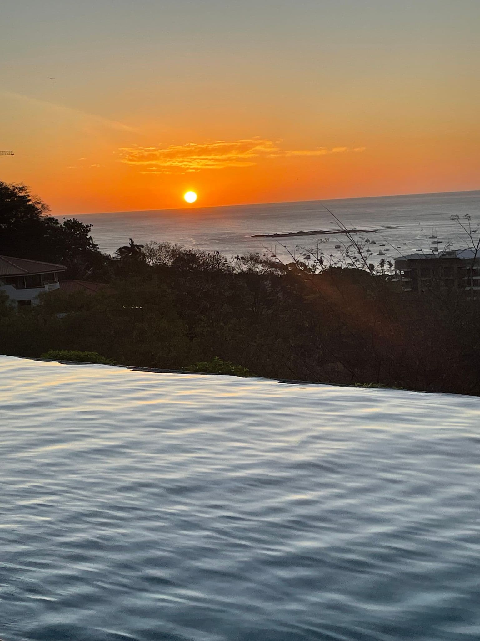 Infinity pool edge with the sun setting over the Pacific at Tamarindo Beach, Costa Rica.