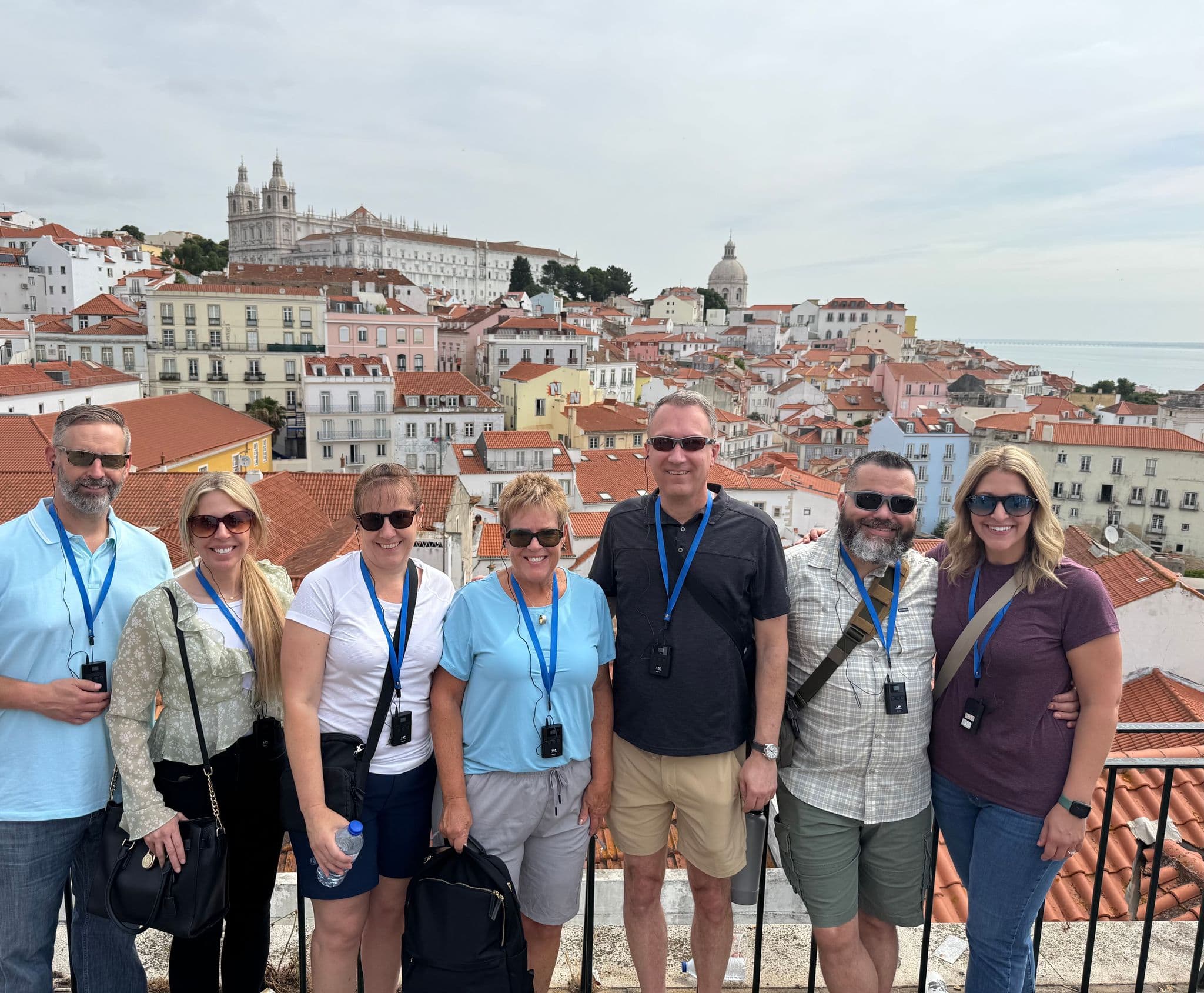 Alfama rooftops and the National Pantheon in Lisbon, Portugal, with a group of travelers posing at a lookout.
