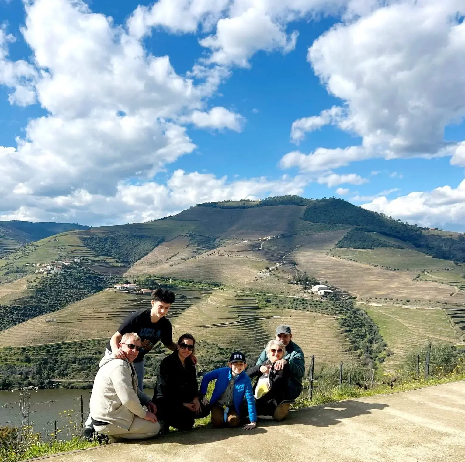 Terraced vineyards of the Douro Valley with a family group posing at a roadside overlook in Portugal.