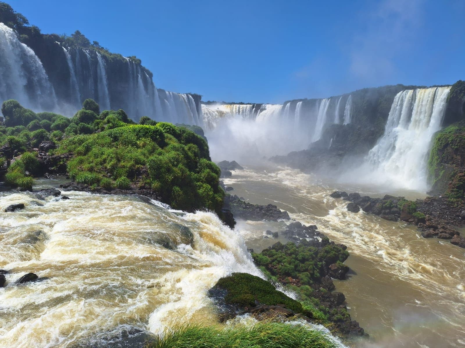 Iguazú Falls cascading over cliffs with mist and a turbulent river below in Argentina.