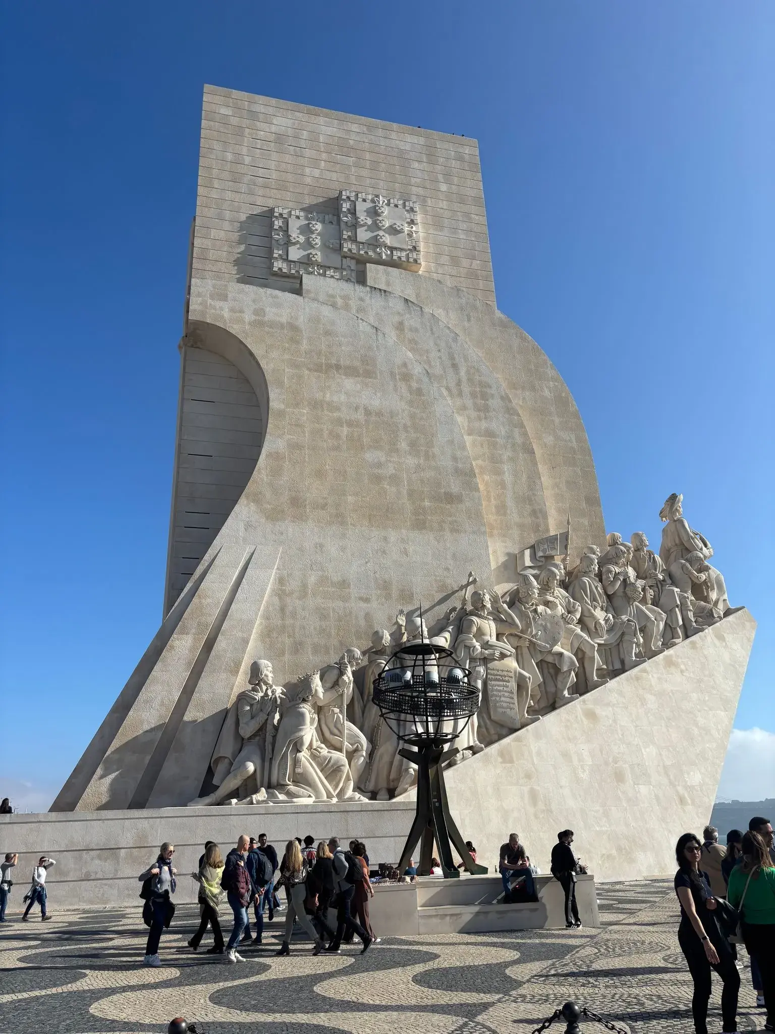 Padrão dos Descobrimentos monument in Belém, Lisbon, Portugal with carved explorers and visitors walking on the patterned plaza.