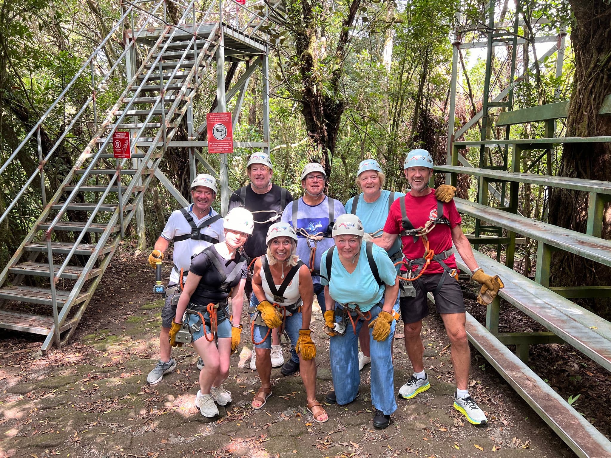 Group of travelers wearing helmets and harnesses posing at a zipline platform in a tropical forest, Costa Rica.