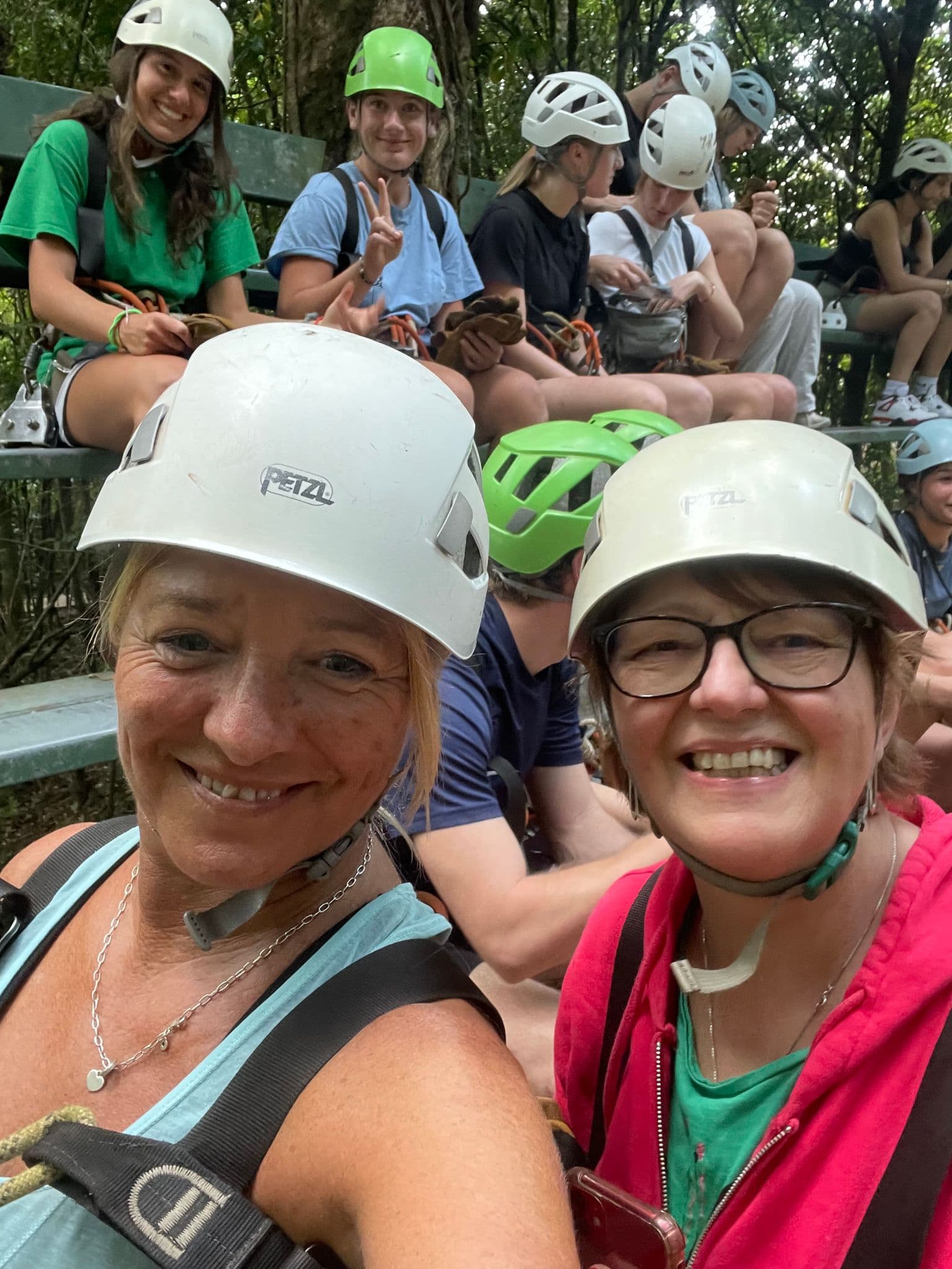 Two women in climbing helmets smiling on a canopy platform during the Monteverde Canopy Tour, Costa Rica.