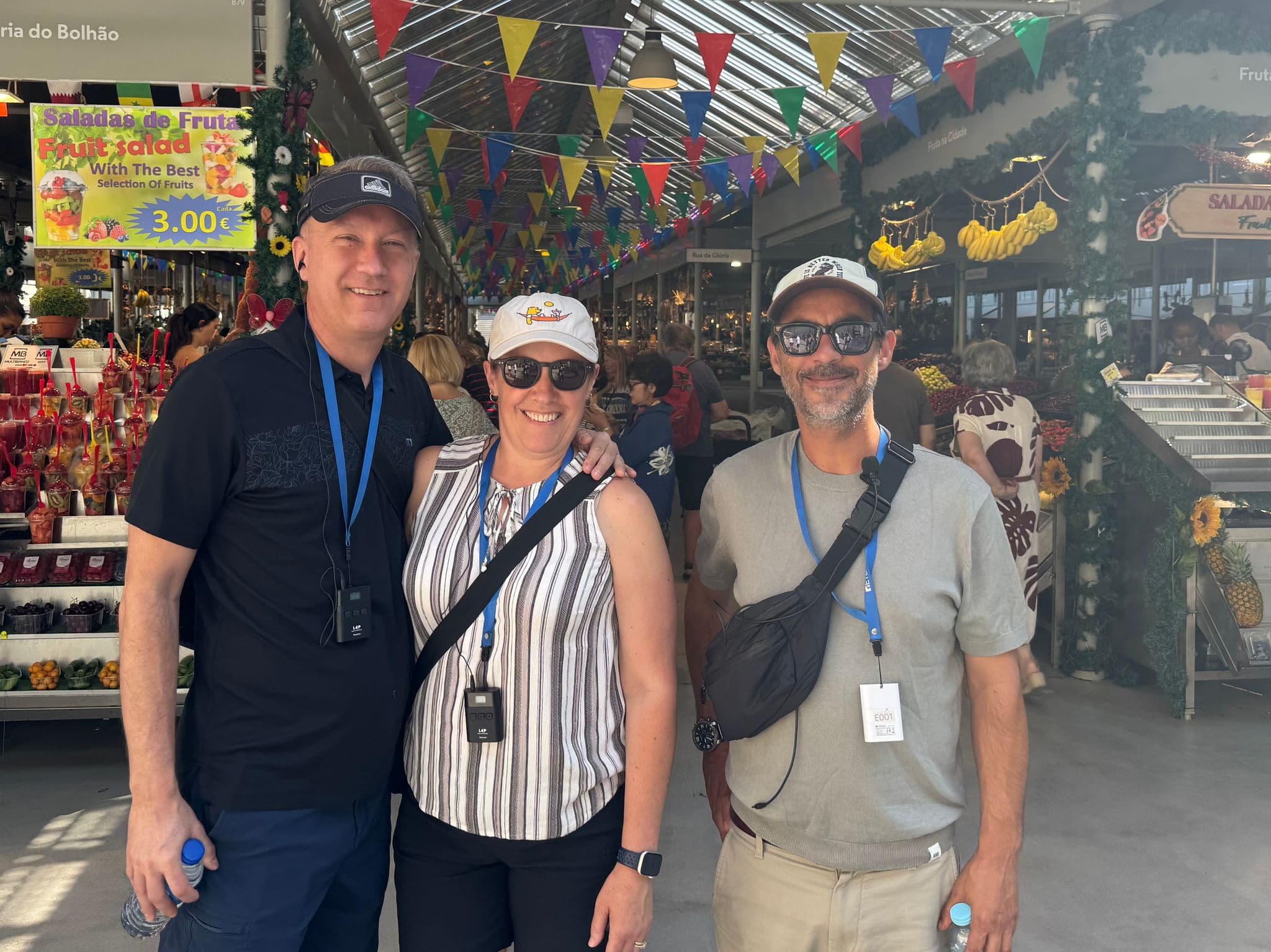 Mercado do Bolhão fruit stalls with three travelers posing in a covered market in Porto, Portugal.