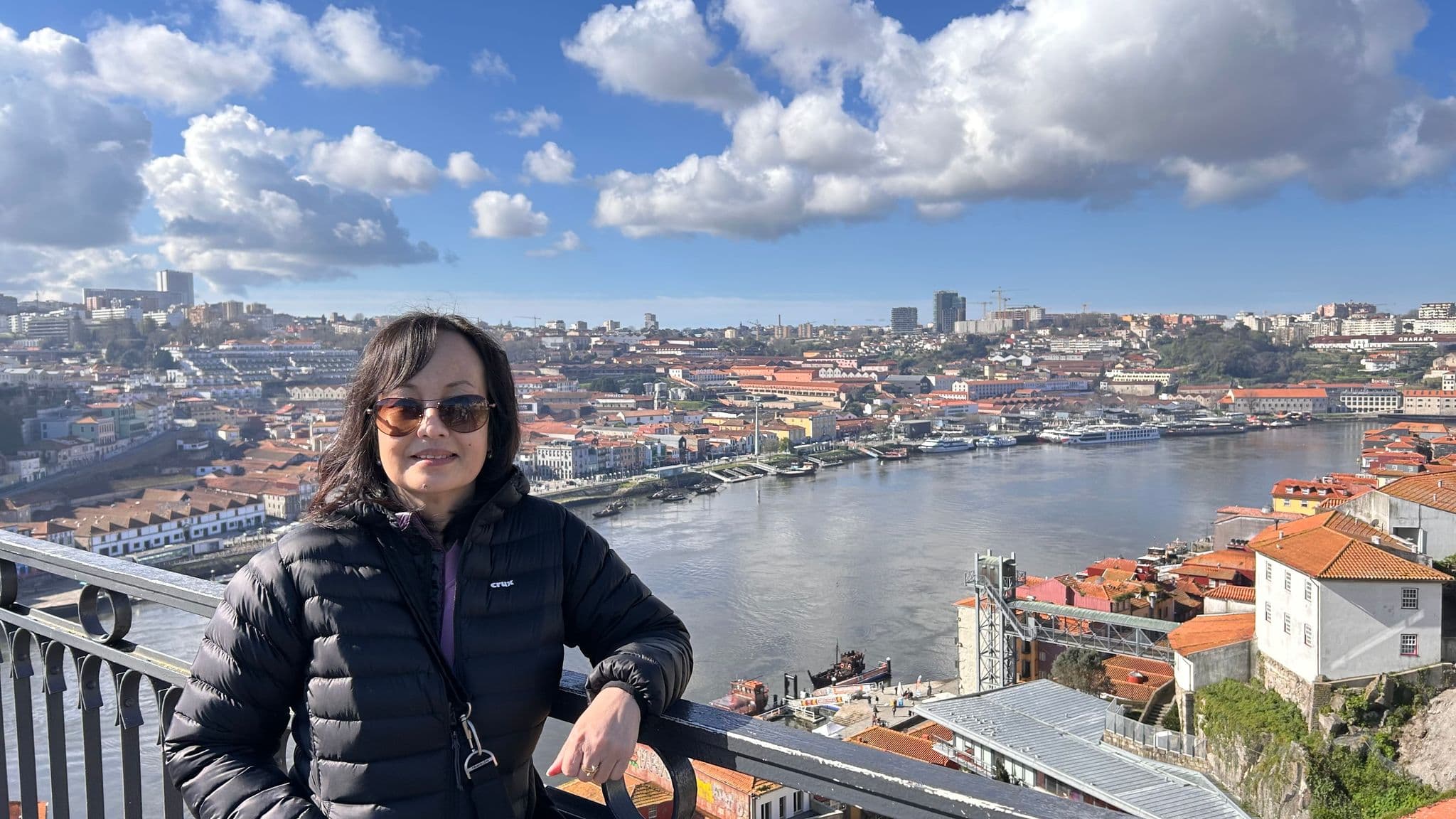 Douro River and Ribeira neighborhood in Porto, Portugal, seen from a bridge with a traveler leaning on the railing.