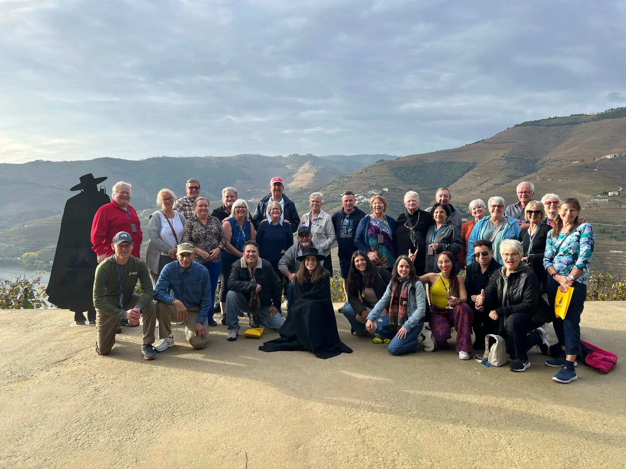 Douro Valley vineyard terraces with a large group of travelers posing at a lookout on a trip, Portugal.