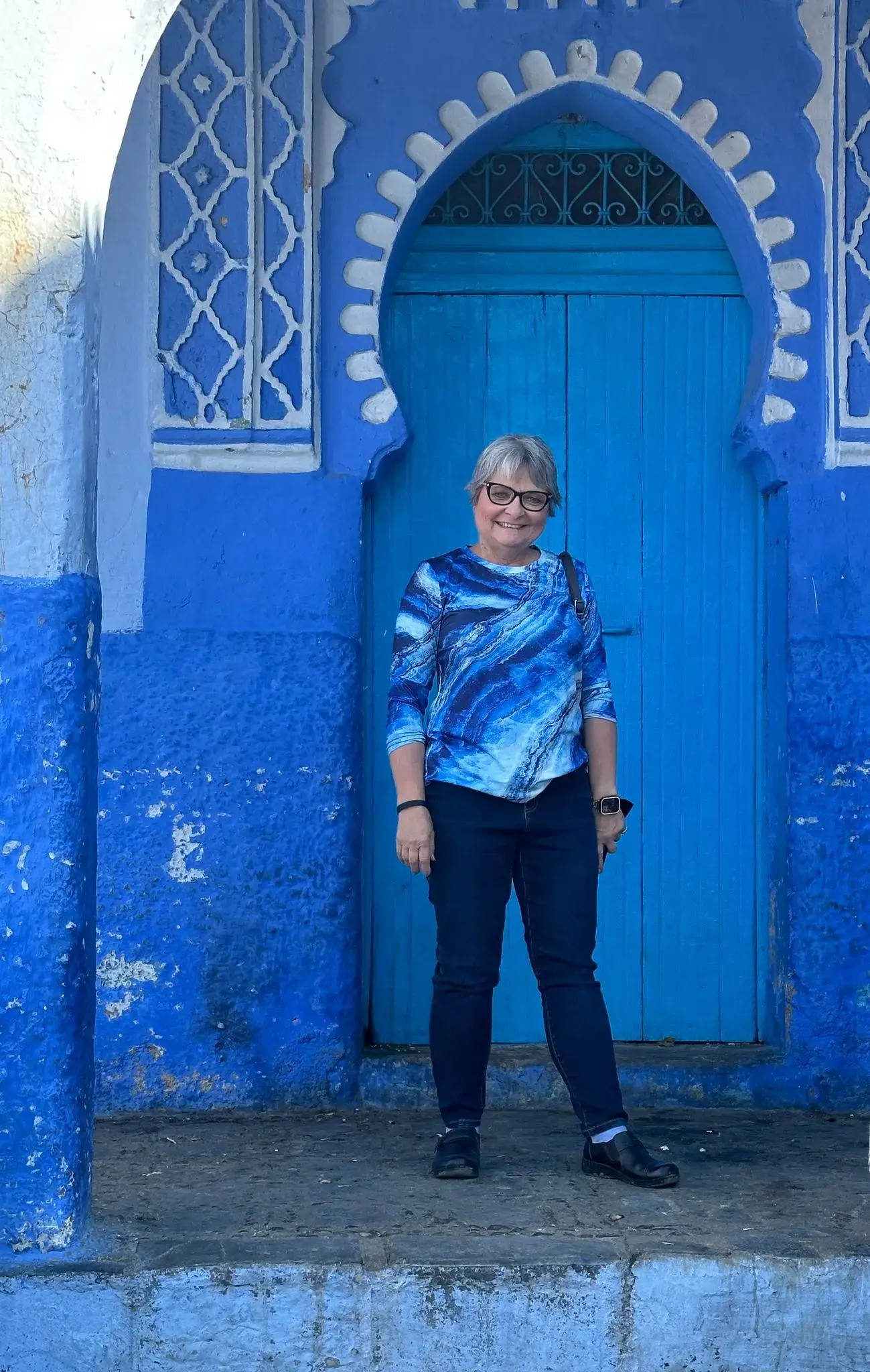 Blue arched doorway in Chefchaouen medina, Chefchaouen, Morocco, with a traveler standing in front