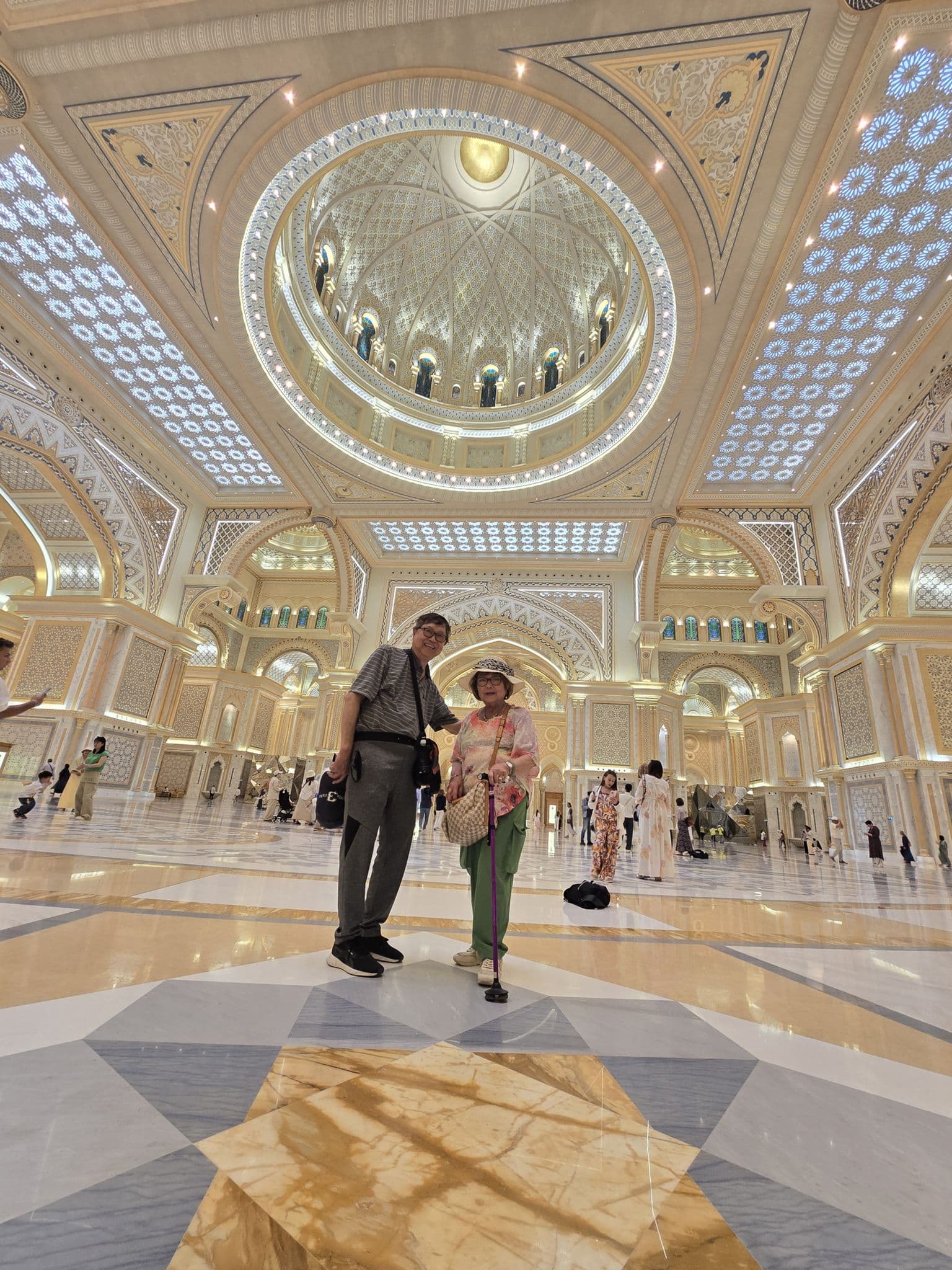 Qasr Al Watan ornate domed hall with two travelers standing on the marble floor, Abu Dhabi, United Arab Emirates.