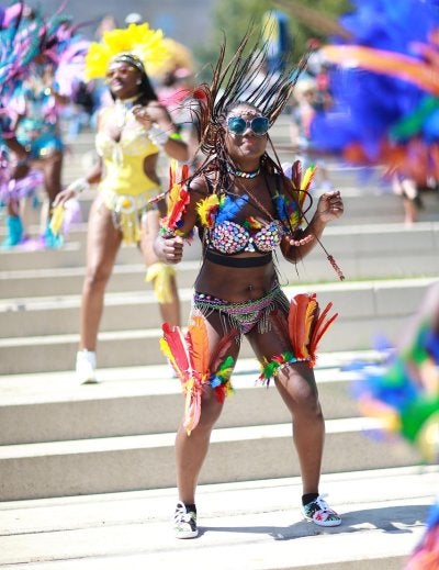 Caribbean carnival dancer in colorful feathered costume performing at street parade