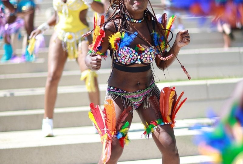 Caribbean carnival dancer in colorful feathered costume performing at street parade