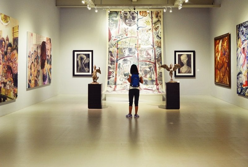 Modern art museum gallery with visitor viewing colorful paintings