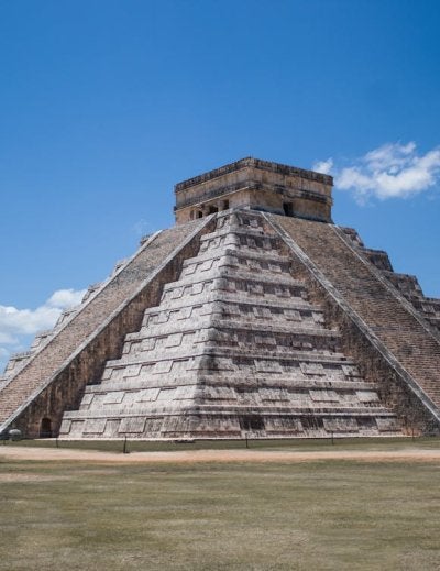 The ancient Mayan pyramid of Kukulcán stands majestically under bright blue skies