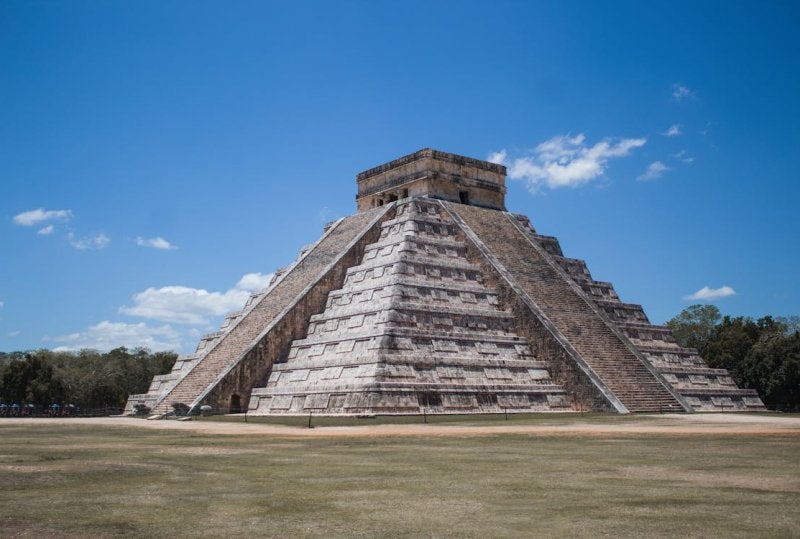 The ancient Mayan pyramid of Kukulcán stands majestically under bright blue skies