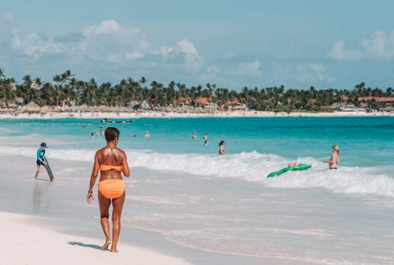 Woman walking on white sand beach with turquoise water and palm trees in Punta Cana