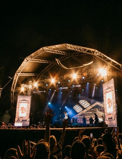 Live band performing on outdoor concert stage at night with crowd and stage lights