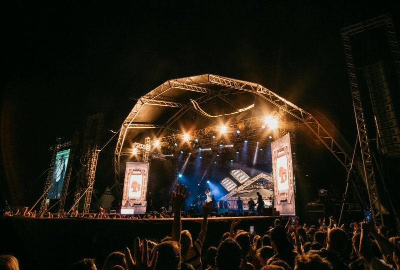 Live band performing on outdoor concert stage at night with crowd and stage lights