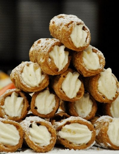 Stack of traditional Sicilian cannoli filled with ricotta cream and dusted with powdered sugar