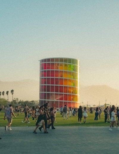 People enjoying a lively music festival with a colorful tower and Ferris wheel backdrop.