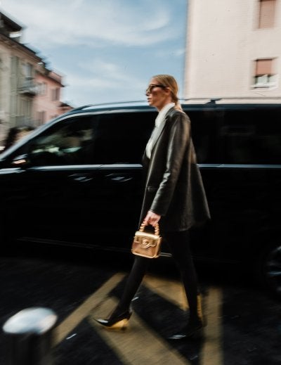 a woman walking across a street holding a purse