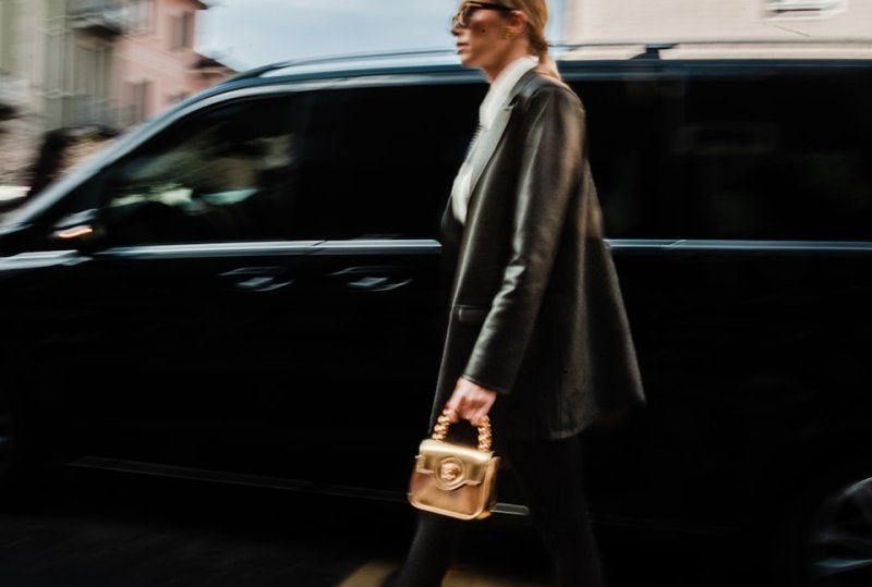a woman walking across a street holding a purse