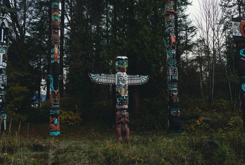 group of totem poles standing in the forest