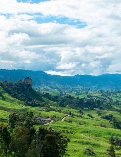 Beautiful landscape showcasing lush green hills under a dramatic cloudy sky, perfect for serene and tranquil backdrops.