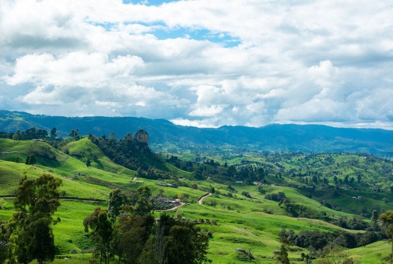Beautiful landscape showcasing lush green hills under a dramatic cloudy sky, perfect for serene and tranquil backdrops.