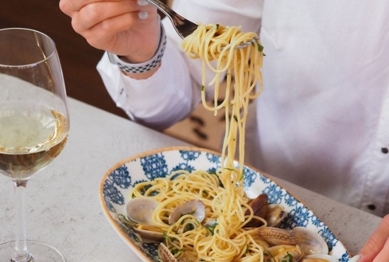 Capture of a gourmet seafood spaghetti meal paired with white wine.